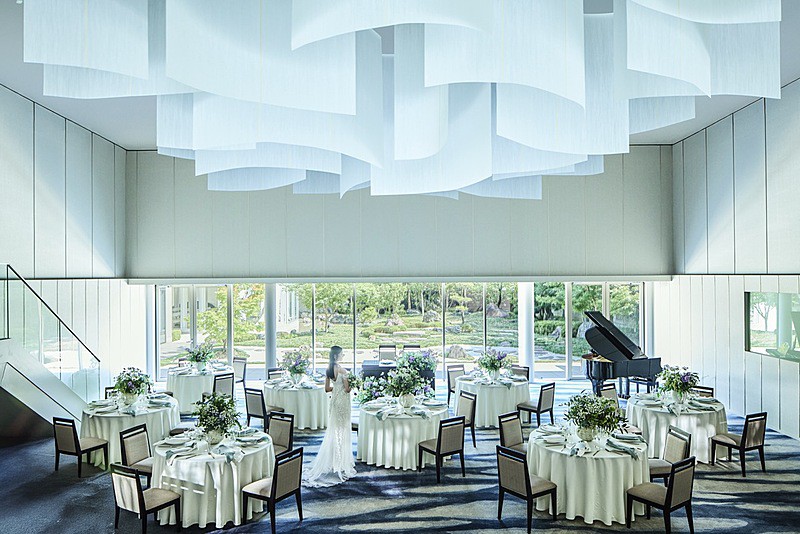 ふたりの背景に四季を彩る庭園を望む披露宴